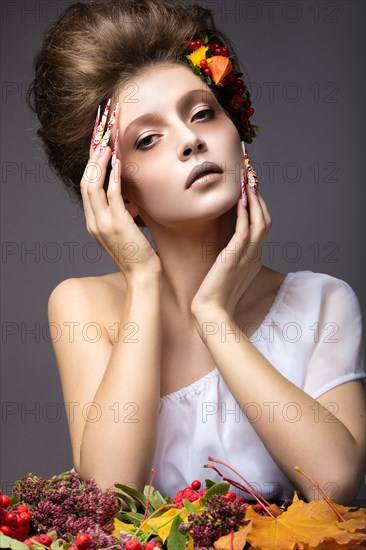 Beautiful girl in autumn image with long nails with bright and unusual make-up. Picture taken in the studio on a gray background