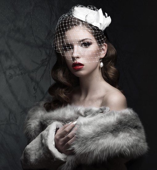 Elegant lady in fur coat with veil and nail Design. Winter image. Picture taken in the studio on a gray background. Beauty face