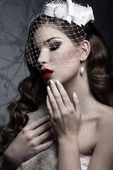 Elegant lady in fur coat with veil and nail Design. Winter image. Picture taken in the studio on a gray background. Beauty face