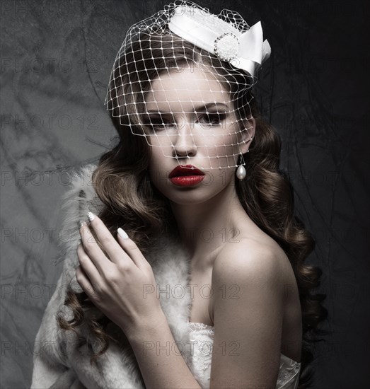 Elegant lady in fur coat with veil and nail Design. Winter image. Picture taken in the studio on a gray background. Beauty face