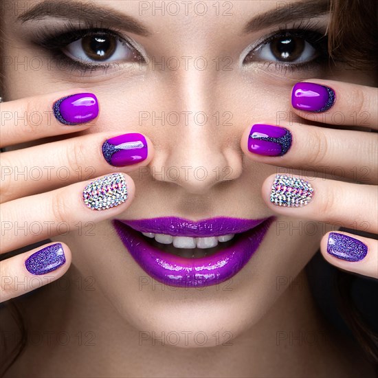 Beautiful girl with a bright evening make-up and purple manicure with rhinestones. Nail design. Beauty face. Picture taken in the studio on a black background