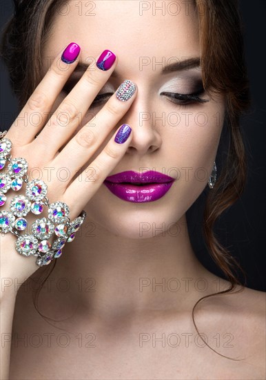 Beautiful girl with a bright evening make-up and purple manicure with rhinestones. Nail design. Beauty face. Picture taken in the studio on a black background