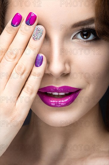 Beautiful girl with a bright evening make-up and purple manicure with rhinestones. Nail design. Beauty face. Picture taken in the studio on a black background