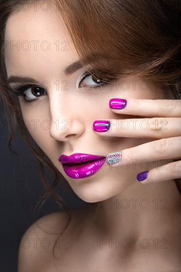 Beautiful girl with a bright evening make-up and purple manicure with rhinestones. Nail design. Beauty face. Picture taken in the studio on a black background