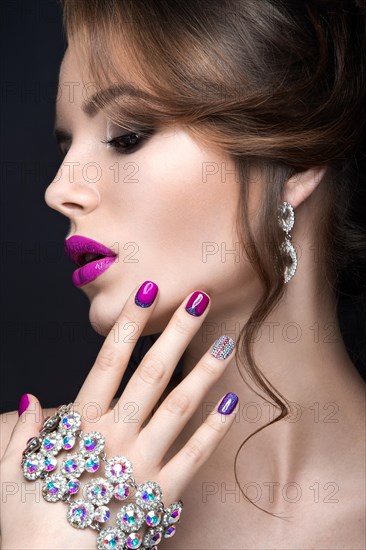 Beautiful girl with a bright evening make-up and purple manicure with rhinestones. Nail design. Beauty face. Picture taken in the studio on a black background