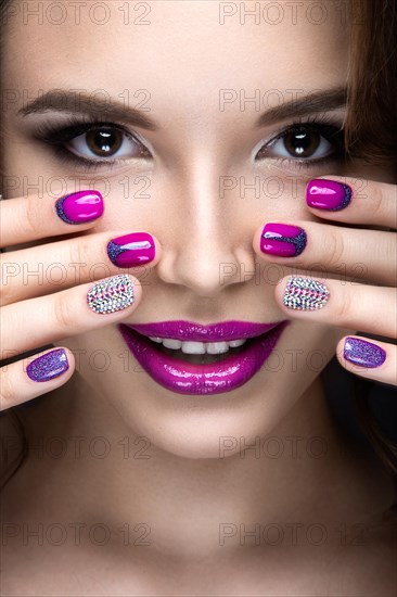 Beautiful girl with a bright evening make-up and purple manicure with rhinestones. Nail design. Beauty face. Picture taken in the studio on a black background