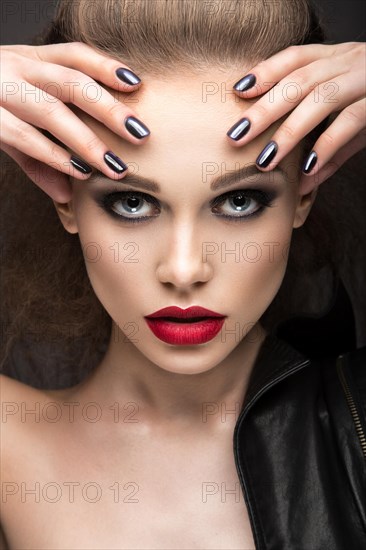 Beautiful girl in leather jacket with bright makeup and manicure Cat's Eye. Beauty face. Nail Design. Picture taken in the studio on a black background