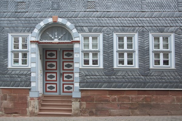 Historic house wall with door and window and slate shingles