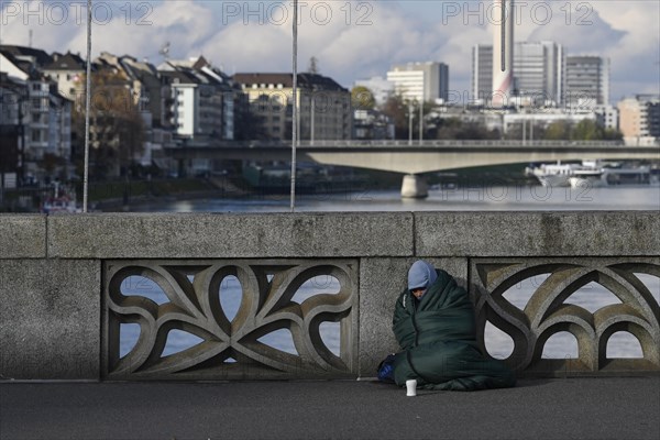 Homeless person with sleeping bag and cup