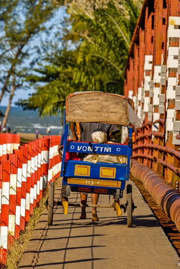 Rickshaw passing a bridge over the Manakara river on the east coast of Madagascar