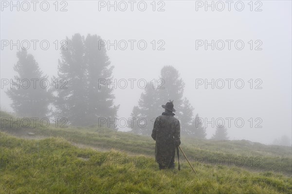 Shepherds standing on a meadow in the rain during the alpine migration