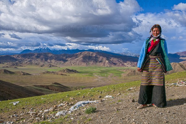 Tibetan woman posing before the mountainous Himalaya landscape along the southern route into Western Tibet