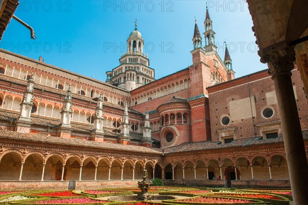 Inner courtyard decorated with planted flowers behind it cloister