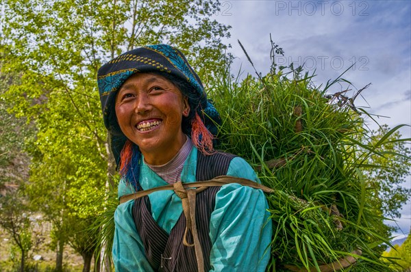 Friendly woman with hay on her back coming back from the field