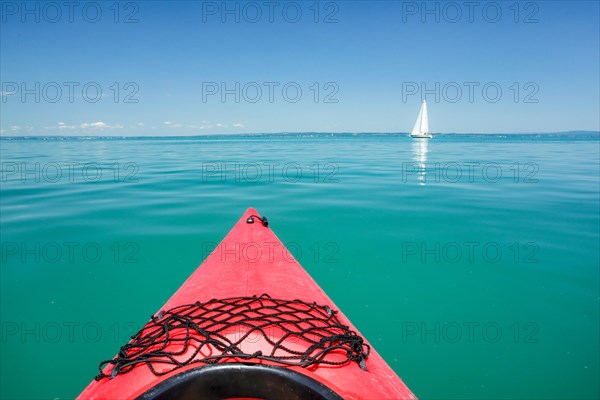 Bow of red kayak with view over the expanse and turquoise waters of Lake Constance