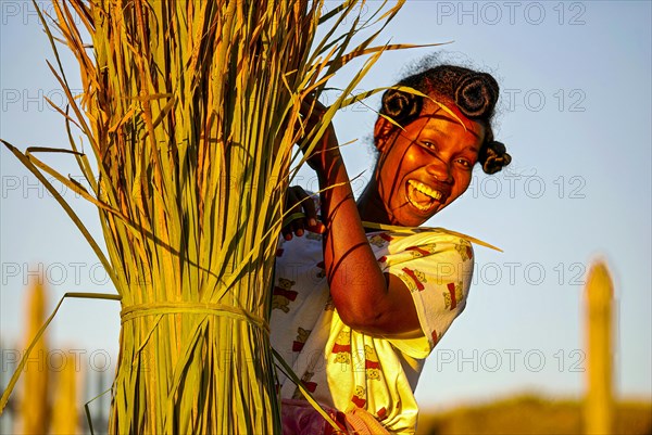 Frau lacht hinter einem Strohballen hervor nach der Ernte