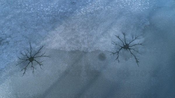 Drone image of so-called steam holes in the ice surface of a frozen lake caused by convection in the water