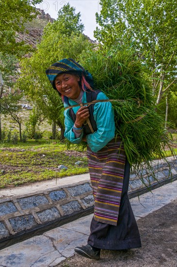 Friendly woman with hay on her back coming back from the field