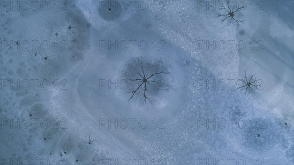 Drone image of so-called steam holes in the ice surface of a frozen lake caused by convection in the water