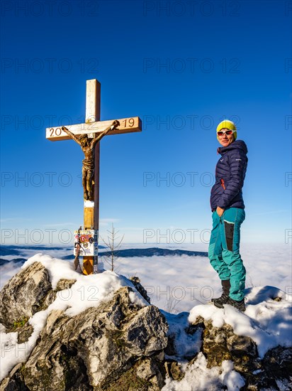 Mountaineer standing at the summit cross of the Mahdlgupf in the snow