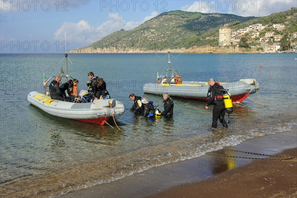 Divers on the beach getting into diving boats inflatables