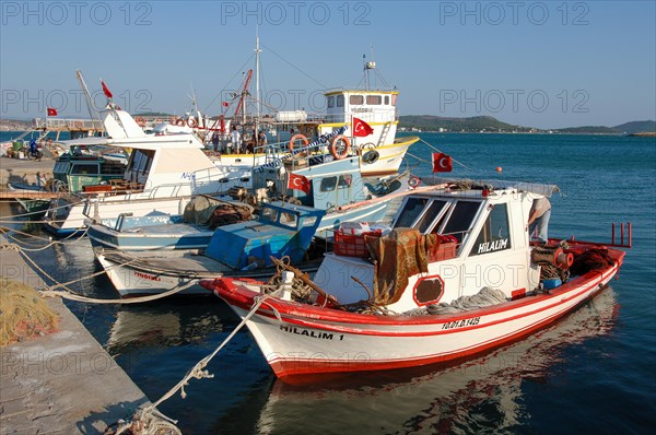 Small Turkish fishing boats moored at quay wall of harbour