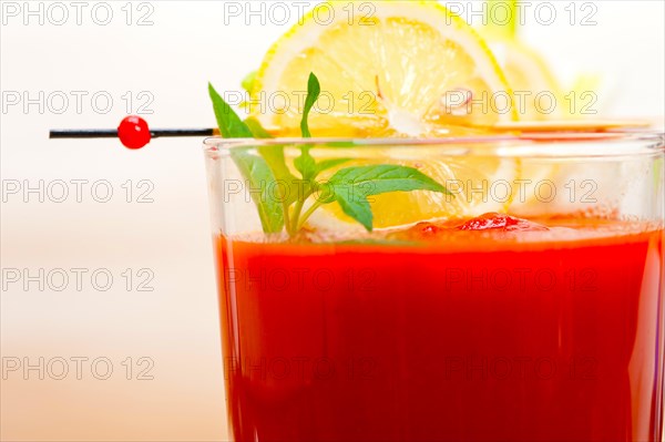 Fresh tomato juice gazpacho soup on a glass over white wood table