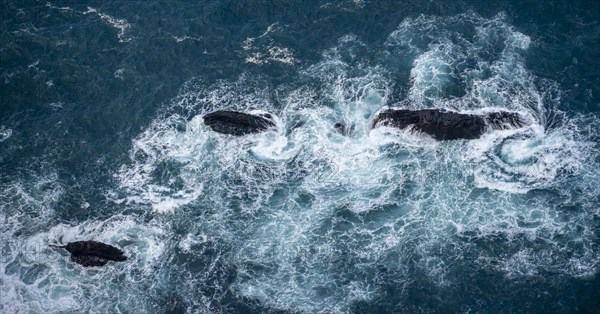 Waves wash around black volcanic rocks