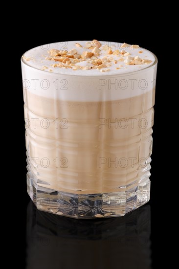 Cappuccino or latte with hazelnut crumbs on black background with reflection
