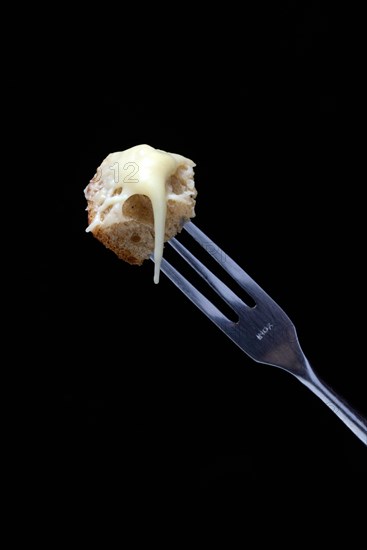 Bread cubes with melted cheese on fondue fork