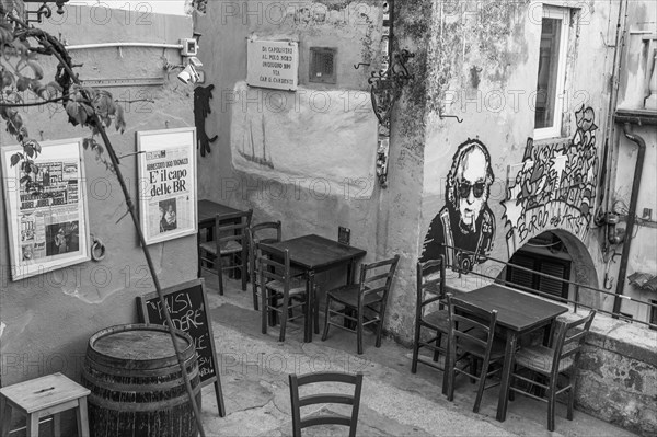 Street cafe with framed historical newspapers and street art in Via Cardenti