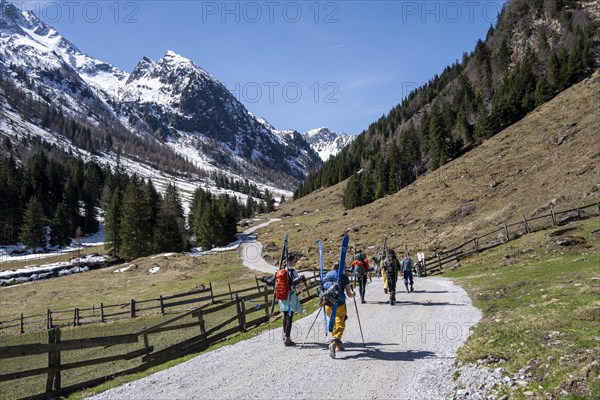 Ski tourers hiking on a road in spring with little snow