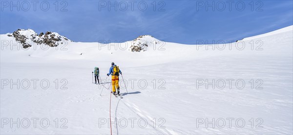 Ski tourers walking on the rope on the glacier