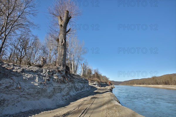 Steep wall of sand and dredge marks on a river bank