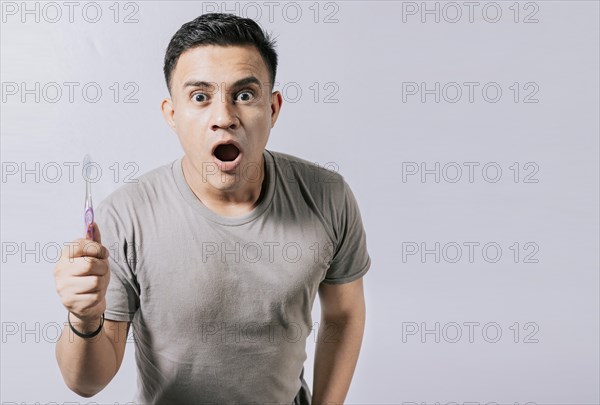 Guy holding toothbrush with amazed face isolated on white