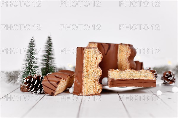 Cut open traditional German layered winter cake called 'Baumkuchen' glazed with chocolate in front of seasonal decoration