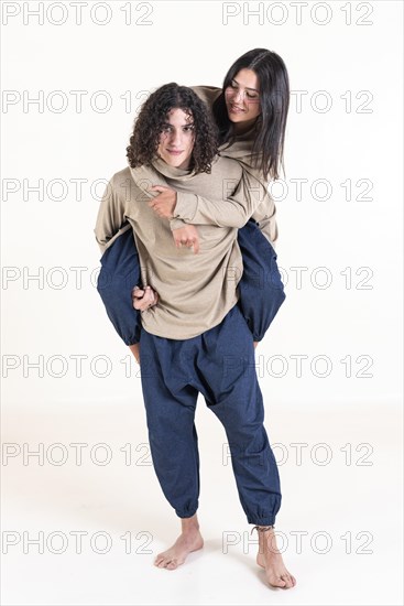 Brother and sister twins matching outfits. A handsome teenager carrying his beautiful sister on his back