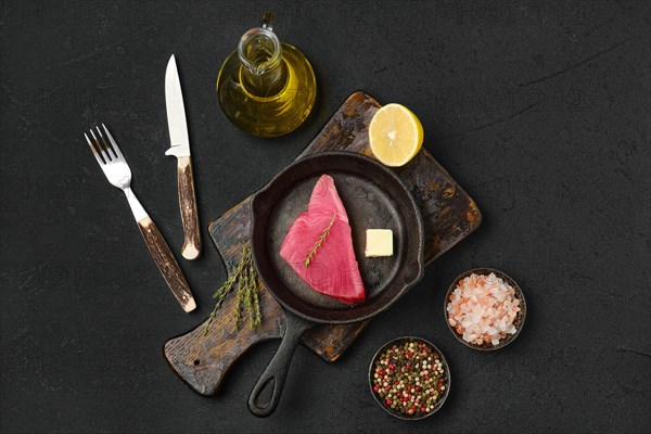 Top view of raw fresh tuna steak in cast iron skillet and spices