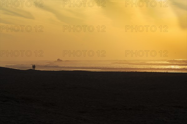 Couple on the beach looking at the ruins of the watchtower Bordj El Berod on the horizon