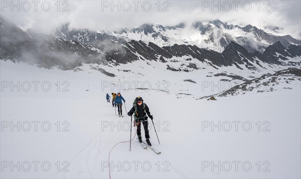 Ski tourers walking on the rope on the glacier in winter in the mountains