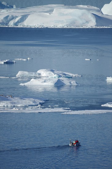 Boat in front of huge icebergs and drift ice
