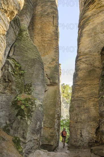 Woman walking through narrow passage at Prachovske rocks