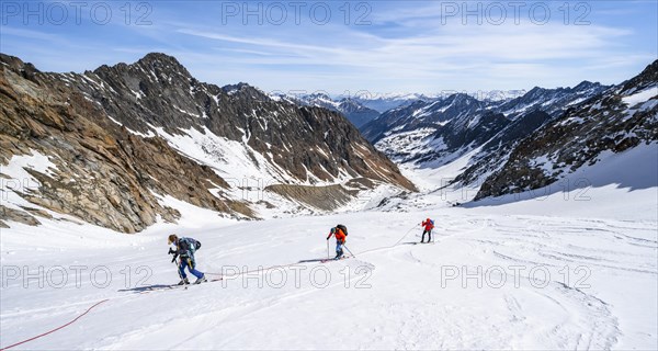 Three ski tourers walking on the rope on the glacier