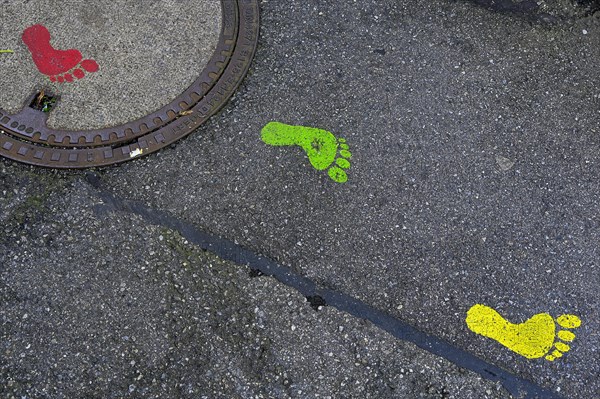 Colourful footprints on manhole covers and asphalt