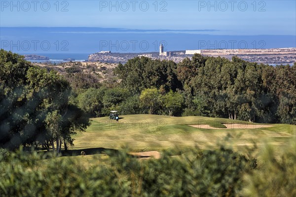 Tourist on golf course overlooking the sea and the ruins of Mogador Island