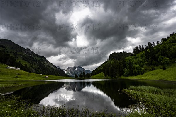 Groeppelensee with reflection of the Altmann summit in the background under a threatening cloudy sky