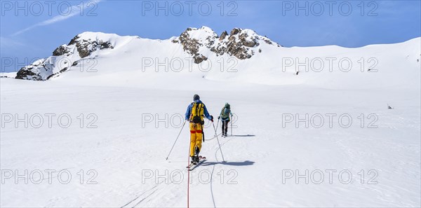 Ski tourers walking on the rope on the glacier