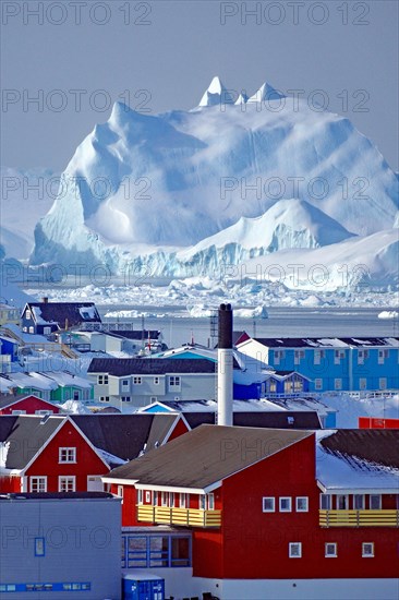 Chimney and different coloured houses in front of huge icebergs