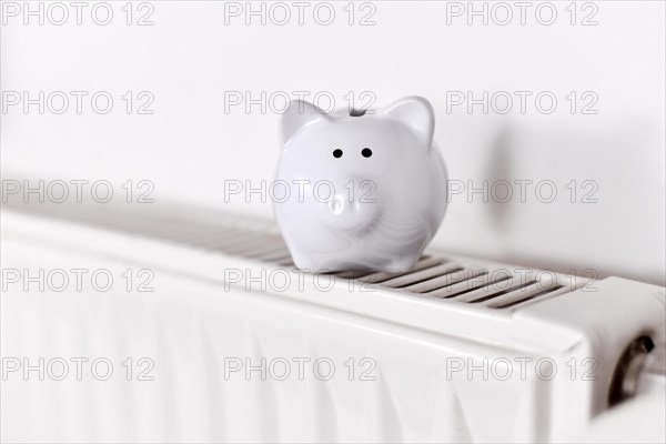 Concept for saving money for gas for heating with piggy bank on radiator with copy space