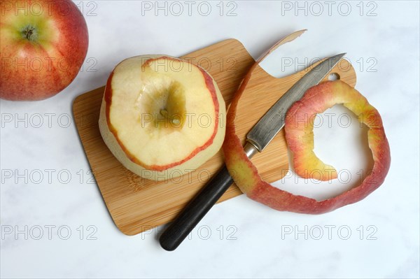 Peeled apple and apple peel with knife